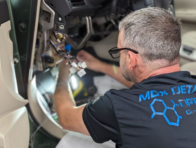Technicians working on vehicles for remote starter and electronics installations